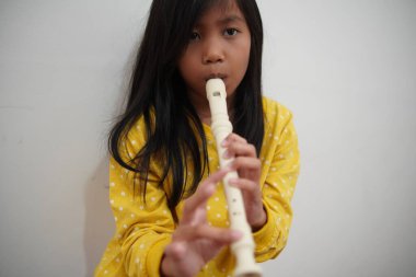 Küçük Asyalı kız flüt çalıyor, müzik aleti.