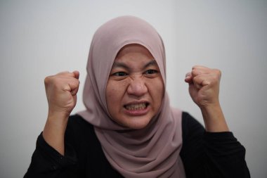 Öfkeli Asyalı Müslüman kadın, öfke ve yoğunluk dolu, çılgın bir ifade.