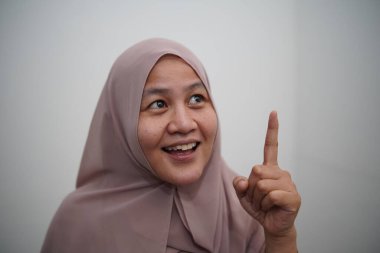 Asyalı Müslüman kadın gülümseyen bir şey düşünüyor, mutlu pozitif, iyi fikir ifadesini işaret ediyor.