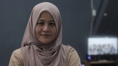 Mutlu kendinden emin Asyalı Müslüman kadın kameraya gülümsüyor, başarılı girişimci, yakın plan portresi