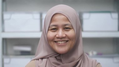 Mutlu kendinden emin Asyalı Müslüman kadın kameraya gülümsüyor, başarılı girişimci, yakın plan portresi