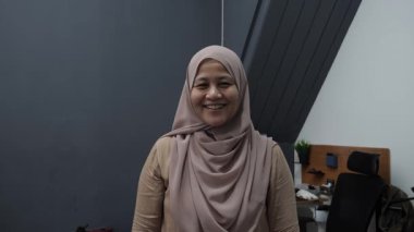 Mutlu kendinden emin Asyalı Müslüman kadın kameraya gülümsüyor, başarılı girişimci, yakın plan portresi