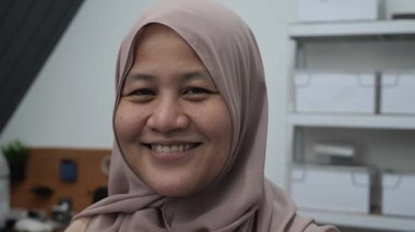 Mutlu kendinden emin Asyalı Müslüman kadın kameraya gülümsüyor, başarılı girişimci, yakın plan portresi