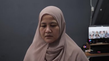 Asyalı müslüman kadın, kızgın suratıyla kameraya bakıyor. Mutsuz jest, yakın plan portre