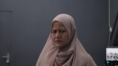 Asyalı müslüman kadın, kızgın suratıyla kameraya bakıyor. Mutsuz jest, yakın plan portre