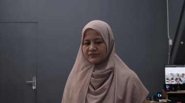 Asyalı müslüman kadın, kızgın suratıyla kameraya bakıyor. Mutsuz jest, yakın plan portre