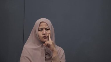 Asyalı Müslüman kadın gülümseyen bir şey düşünüyor, mutlu pozitif, iyi fikir ifadesini işaret ediyor.