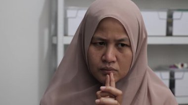 Asyalı Müslüman kadın gülümseyen bir şey düşünüyor, mutlu pozitif, iyi fikir ifadesini işaret ediyor.