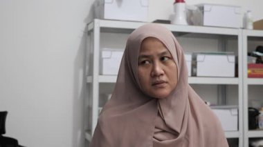 Asyalı Müslüman kadın gülümseyen bir şey düşünüyor, mutlu pozitif, iyi fikir ifadesini işaret ediyor.