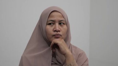 Asyalı Müslüman kadın gülümseyen bir şey düşünüyor, mutlu pozitif, iyi fikir ifadesini işaret ediyor.