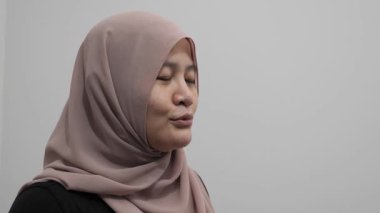 Asyalı Müslüman kadın konuşuyor, bir şeyler anlatıyor ya da konuşma yapıyor, yan görüş, mutlu gülümseme ifadesi.