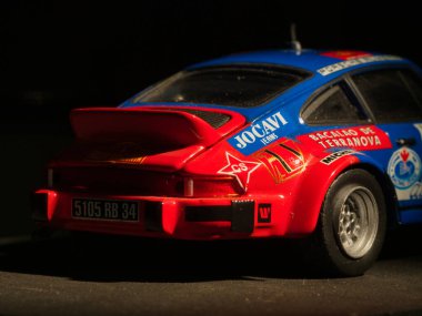 Vintage Rally Car Model Dark Background - Sponsorluk çıkartmalı klasik bir Porsche ralli arabasının detaylı ve renkli bir kopyası, koyu bir arka plana çarpıyor. Yarış ve hobi konsepti.