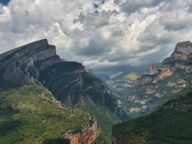 Dramatik Gökyüzü ile Yüksek Dağ Geçidi - Dik, kayalık uçurumlar arasında oyulmuş derin vadi ve kanyon ve yoğun ormanlarla kaplı karanlık, güçlü fırtına bulutları altında.