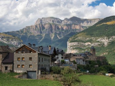 Yüksek Dağ Köyü ve Dramatik Uçurumlar - Kırsal taştan köy ve kilise kulesi muhteşem uçurumları ve arka planda yükselen kayalık dağları olan yemyeşil bir vadiye kurulmuş.