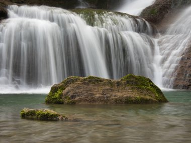 Şelalenin Kayalıklardan Aşağı Şelale 'ye yakın çekim - Uzun pozlama kullanarak ipeksi, pürüzsüz bir su efekti yaratarak dokuma, kırmızımsı kahverengi kaya oluşumlarını havuza doğru akıtmak.