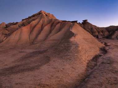 Golden Hour 'daki soyut Çöl Çorak Toprakları Dokusu- Sert bir kenar altında aşınmış kil ve kumtaşı tepelerinin ve çorak toprakların tepelerinin çarpışması güçlü çapraz gölgeler oluşturur..