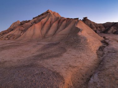 Golden Hour 'daki soyut Çöl Çorak Toprakları Dokusu- Sert bir kenar altında aşınmış kil ve kumtaşı tepelerinin ve çorak toprakların tepelerinin çarpışması güçlü çapraz gölgeler oluşturur..