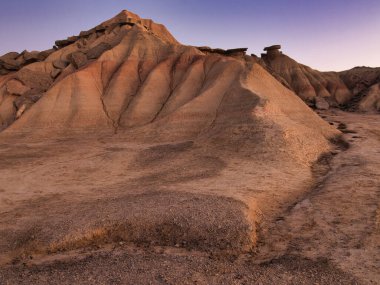 Golden Hour 'daki soyut Çöl Çorak Toprakları Dokusu- Sert bir kenar altında aşınmış kil ve kumtaşı tepelerinin ve çorak toprakların tepelerinin çarpışması güçlü çapraz gölgeler oluşturur..