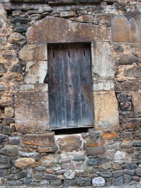 Eski Ahşap Pencereli Kırsal Taş Duvar - Kapalı, kırsal ve hasarlı ahşap pencere çerçevesi ve kepenkleri olan yıpranmış taş duvar dokusu. Geleneksel Avrupa mimari ayrıntıları.