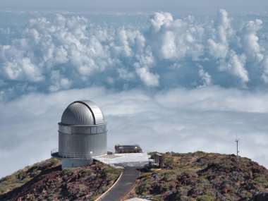 Dağdaki Gümüş Astronomik Gözlemevi - Yüksek rakımlı astronomik gözlemevi Dağ sırtında gümüş bir kubbe, bulutlara ve açık mavi gökyüzünün altındaki okyanusa bakan.