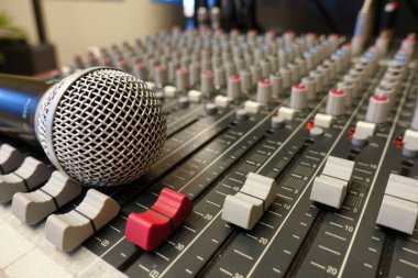 Bir ses karıştırma konsolundaki mikrofonun dinamik yakın çekimi - canlı müzik, podcast, yayıncılık veya stüdyo kayıt oturumlarında kullanılan profesyonel ses mühendisliği ekipmanı.