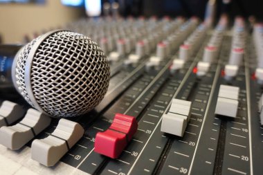 Bir ses karıştırma konsolundaki mikrofonun dinamik yakın çekimi - canlı müzik, podcast, yayıncılık veya stüdyo kayıt oturumlarında kullanılan profesyonel ses mühendisliği ekipmanı.