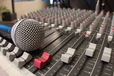 Bir ses karıştırma konsolundaki mikrofonun dinamik yakın çekimi - canlı müzik, podcast, yayıncılık veya stüdyo kayıt oturumlarında kullanılan profesyonel ses mühendisliği ekipmanı.