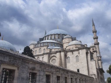 Osmanlı Mezarlığı Tombstone ve Trbe Tarihi Osmanlı mezar taşları, el yazısı ve oymalarla dolu, kubbeli bir mozole (trbe) tarafından çerçevelenmiş, huzurlu bir mezarlıkta yeşillikler arasında duruyor.).