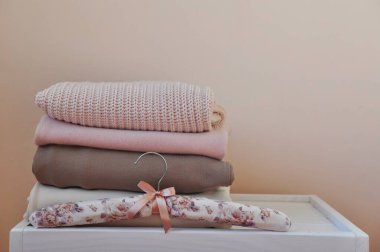 Açık beyaz ahşap masada bir yığın kalın kazak ve pantolon. Metin için boşluk