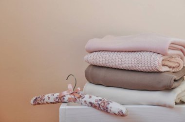 Açık beyaz ahşap masada bir yığın kalın kazak ve pantolon. Metin için boşluk