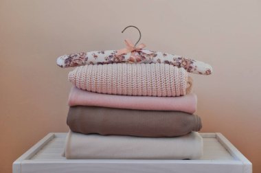 Açık beyaz ahşap masada bir yığın kalın kazak ve pantolon. Metin için boşluk