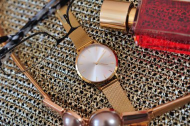 Parlak maddenin üzerinde altın saat, cam ve kırmızı parfümlerden oluşan lüks bir iş. Soyut iş geçmişi