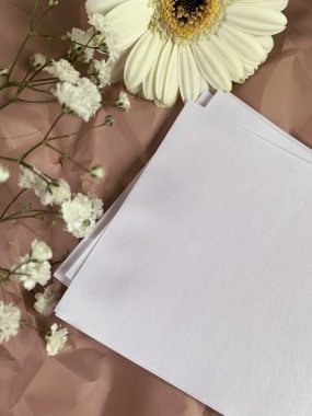 Beyaz çiçekli, bej arka planda beyaz bir kağıt. Düğün metnin için fotokopi çekilen kadın eli üzerine beyaz bir kağıt. Romantik bir fon. Klasik Sevgililer Günü geçmişi