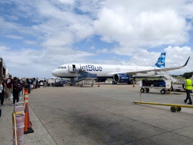 San Juan, Porto Riko - 24 Mart 2022: Dış rampa üzerinden Jet mavi uçağa binen insanlar.