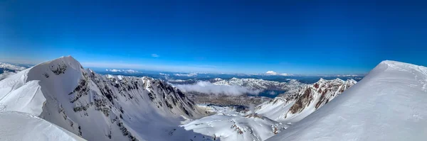 Mount St. Helens Crater viewed from summit, on a sunny winter day, with Sprit Lake and Mount Rainier in the background.