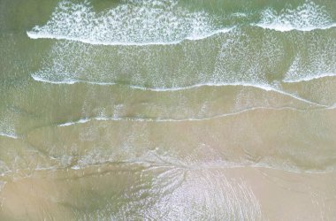 Kıyıya ulaşan okyanus dalgaları ile havadan drone üst görünümünde Plaj.