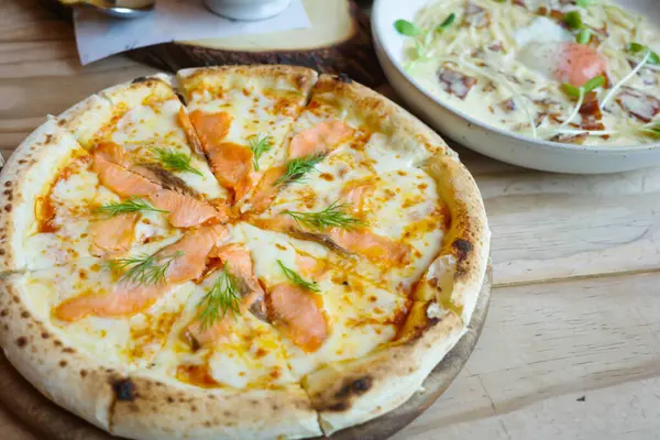 Somon füme ile nefis sıcak pizza, ahşap masada yemeye hazır. Somon ve mozzarella ile tütsülenmiş somon pizzası. Somon füme pizza. 