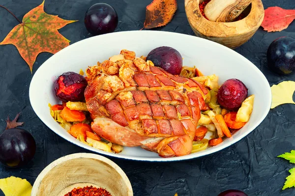 Tasty pork shoulder with skin and bacon grilled with vegetables and plums.