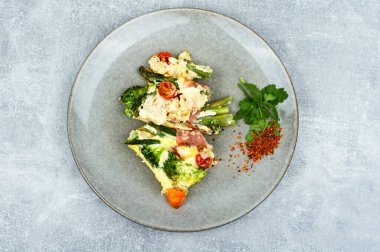 Pastırmaya sarılmış kuşkonmaz, domates, brokoli ve peynirle pişirilmiş..