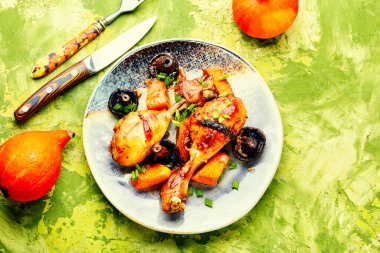 Kabakla süslenmiş bir masada balkabağıyla kızartılmış tavuk bacakları.