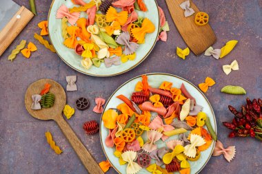 Tabakta renkli İtalyan çiğ makarnası. Renkli makarna yığını.