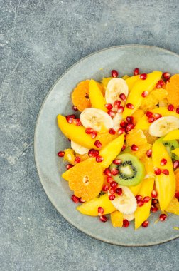 Salad of mango, citrus, banana and berries in a bowl. Healthy fresh fruit salad
