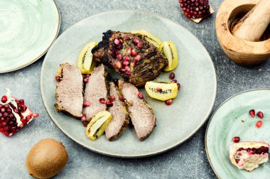 Stewed veal meat in kiwi and pomegranate on a plate