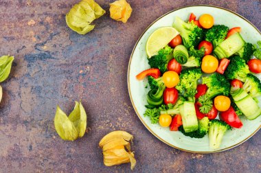 Fresh salad with broccoli, tomato, cucumber and physalis. Vegetarian food