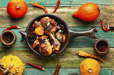 Grilling chicken legs with fried pumpkin on wooden table. Autumn recipe. Top view