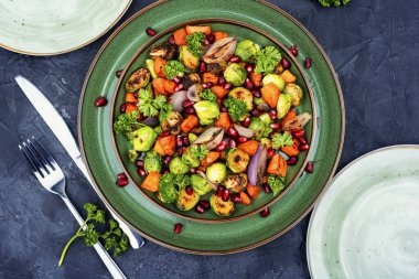 Salad with grilled brussels sprouts, roasted carrots, garnished with herbs and pomegranate seeds. Top view