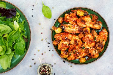 Spicy chicken wings with vegetables and green salad. Top view