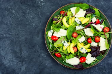 Dietetic salad with fresh lettuce, greens, avocado, tomatoes and cheeses. Copy space