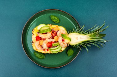 Colorful salad in pineapple with rice, vegetables and shrimps on the table