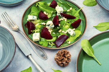 Salad with beets, blue cheese, greens and pine nuts on the plate. Proper nutrition.